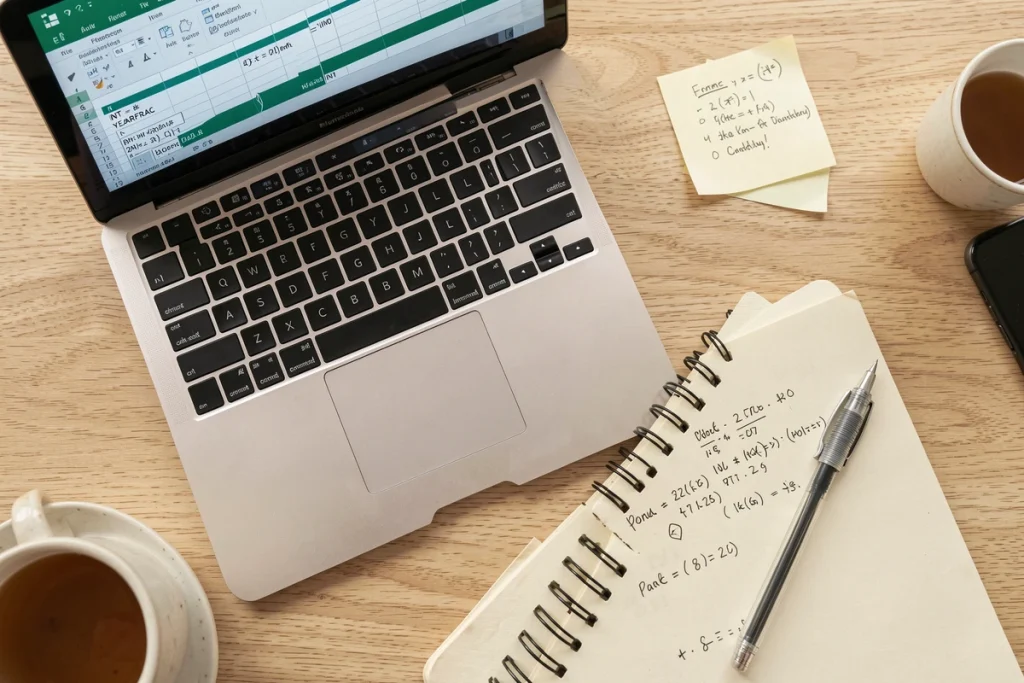 Vue aérienne d'un bureau minimaliste avec un ordinateur portable affichant des formules Excel alternatives pour calculer un âge sans DATEDIF